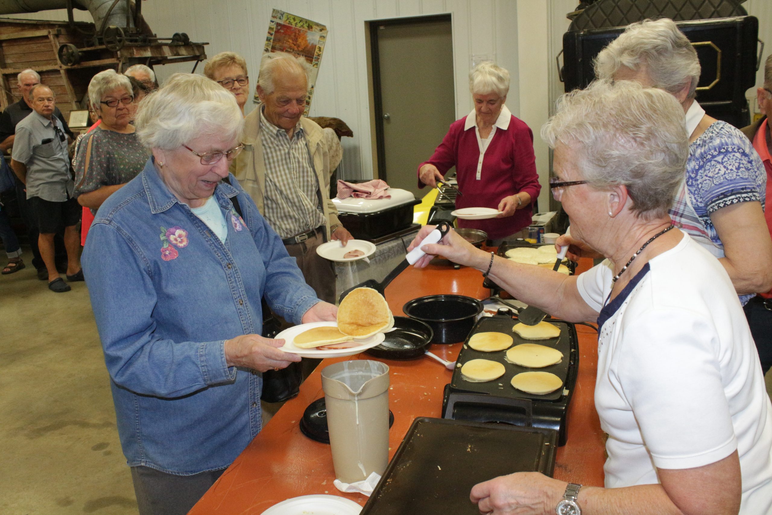 Image of volunteers serving pancakes at a breakfast at Westlock Pioneer Museum